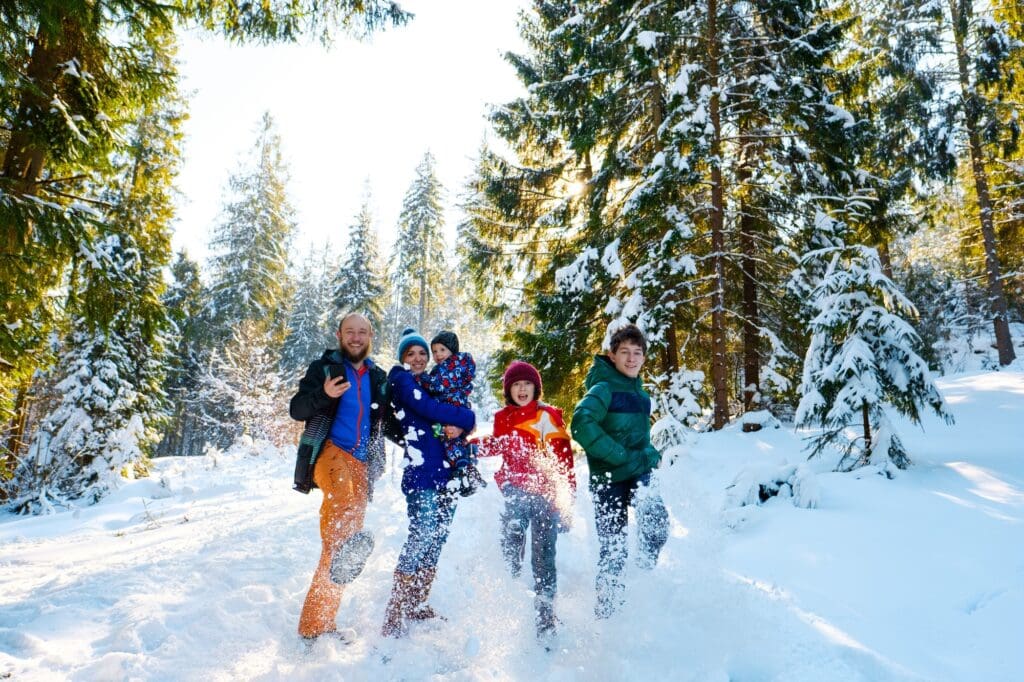 Happy people having fun and playing with snow outdoors in winter nature. Family Christmas holiday walk in a snowy park on ski resort with children. Winter park family friendly ski destination