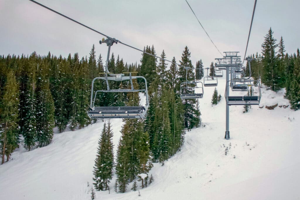 Empty ski lift at resort in Vail Colorado surrounded by green trees