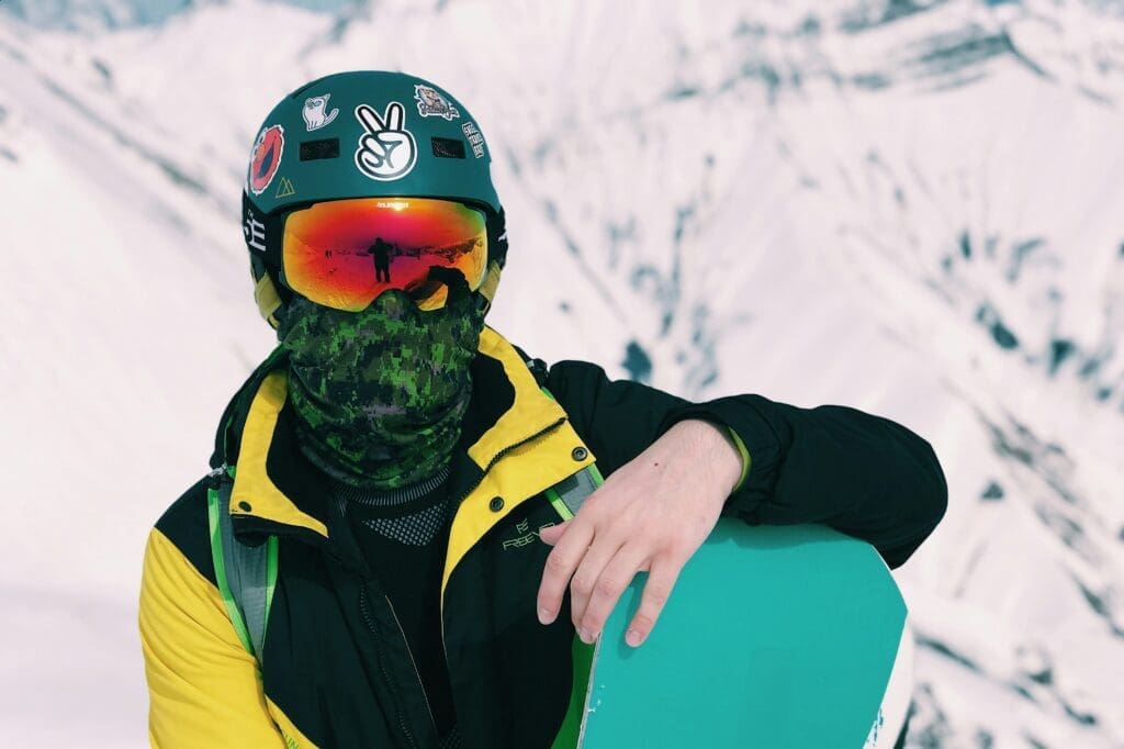 Person in a helmet at goggles leans on a snowboard